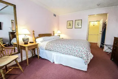 a bedroom with a bed and a table and a mirror at Blairpen House Country Inn in Niagara on the Lake