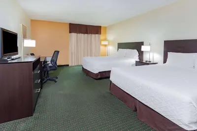 a hotel room with two beds and a flat screen tv at Travelodge by Wyndham Bracebridge in Bracebridge