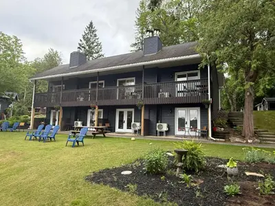 a large house with blue chairs in the yard at Bonnie View Inn in Haliburton