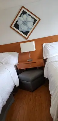 a bedroom with two beds and a table with a lamp at Niagara Inn in Niagara Falls