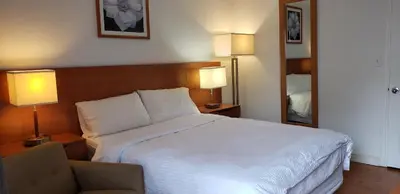 a bedroom with a bed and a chair and two lamps at Niagara Inn in Niagara Falls