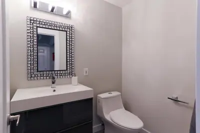 a white bathroom with a toilet and a mirror at Boardwalk Homes - Executive Guest Rooms & Townhomes in Kitchener