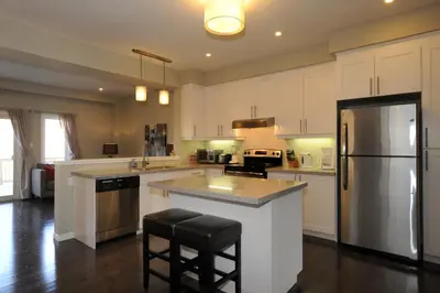 a large kitchen with white cabinets and a refrigerator at Boardwalk Homes - Vacation Homes & Executive Suites in Kitchener