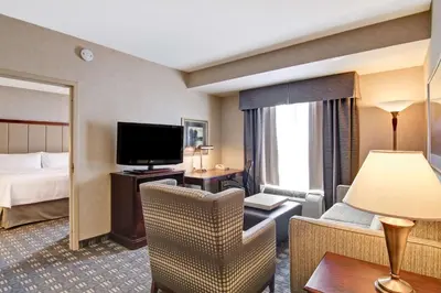 a hotel room with a bedroom with a bed and a television at Homewood Suites by Hilton Toronto Oakville in Oakville