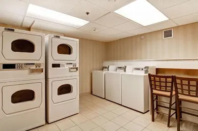 a laundry room with washing machines and a table and chairs at Homewood Suites by Hilton Toronto Oakville in Oakville