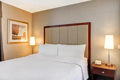 a large bed in a hotel room with two lamps at Homewood Suites by Hilton Toronto Oakville in Oakville