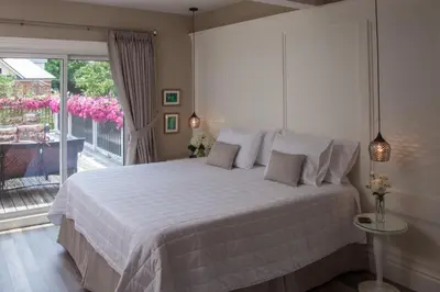 a bedroom with a bed and a balcony with pink flowers at Avery House B&B in Stratford