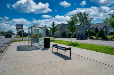 a bus stop with a bench on a sidewalk at Fullerton Manor Inn in Niagara Falls