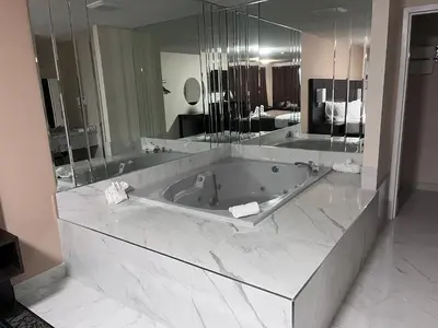 a large bathroom with a tub and a large mirror at Falls Lodge & Suites in Niagara Falls