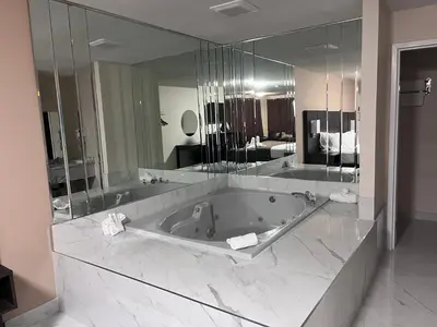 a large bathroom with a tub and a large mirror at Falls Lodge & Suites in Niagara Falls