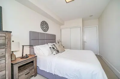 a bedroom with a white bed and a wooden night stand at CHOL Furnished Suites Heart of Downtown Toronto, 2 Beds, Free Parking, CN Tower View in Toronto