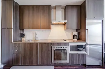 a kitchen with wooden cabinets and a stainless steel refrigerator at CHOL Furnished Suites Heart of Downtown Toronto, 2 Beds, Free Parking, CN Tower View in Toronto