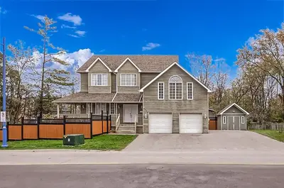 a brown house with a fence in a driveway at 6 Bedroom Executive Cottage near Innisfil Beach Park in Innisfil