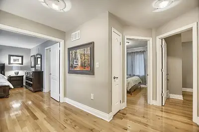 an empty living room with a bed and a room with wood floors at 6 Bedroom Executive Cottage near Innisfil Beach Park in Innisfil