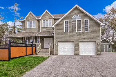 a house with two garage doors on a driveway at 6 Bedroom Executive Cottage near Innisfil Beach Park in Innisfil