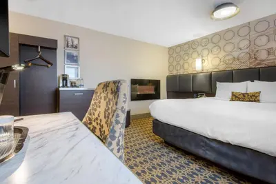 a hotel room with a large bed and a table at The Champlain Waterfront Hotel, an Ascend Collection Hotel in Orillia