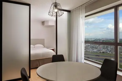 a bedroom with a bed and a table and a window at Hilton Toronto Airport Hotel & Suites in Mississauga