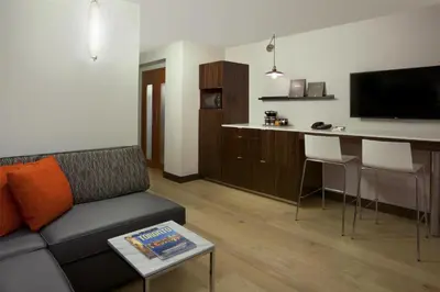 a living room with a couch and a kitchen with a bar at Hilton Toronto Airport Hotel & Suites in Mississauga
