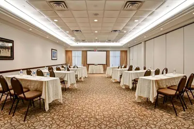 a conference room with tables and chairs and a screen at Hilton Garden Inn Toronto/Burlington in Burlington