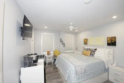 a white bedroom with a bed and a television at Serene Niagara Inn in Niagara Falls