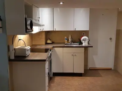a small kitchen with white cabinets and a sink at McMaster Accommodations in Hamilton