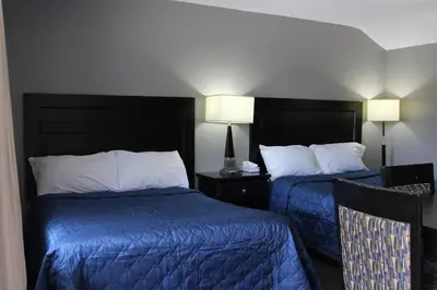 a hotel room with two beds with blue sheets at Super 7 Motel London in London
