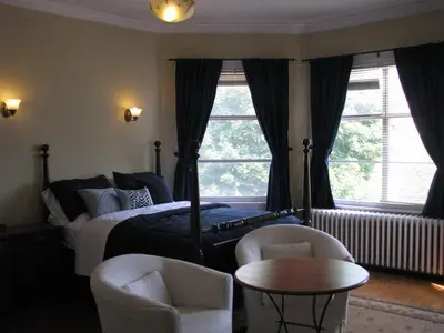 a bedroom with a bed and two chairs and a table at McBayne House in Hamilton