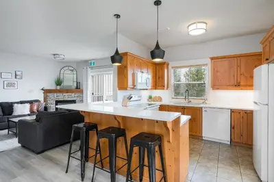 a kitchen with wooden cabinets and a kitchen island with bar stools at Beautiful & Bright 3 Bed Townhome Near Village in Blue Mountains