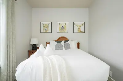 a bedroom with a white bed with four pictures on the wall at Beautiful & Bright 3 Bed Townhome Near Village in Blue Mountains
