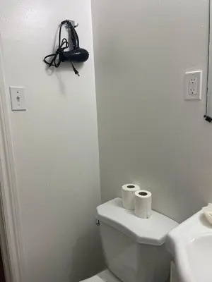 a white bathroom with a toilet and two rolls of toilet paper at London Residency Inn in London