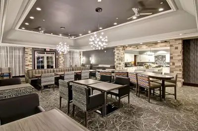 a restaurant with tables and chairs and a bar at Homewood Suites by Hilton Burlington in Burlington