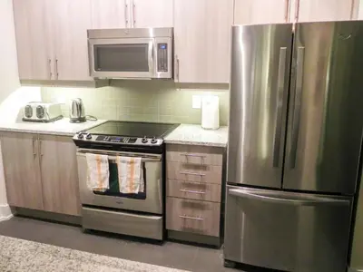 a kitchen with a stainless steel refrigerator and a microwave at Pathway Suites in Mississauga