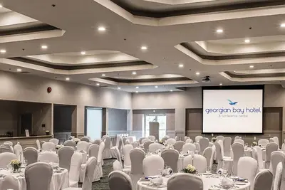 a conference room with white tables and chairs and a screen at Georgian Bay Hotel Trademark Collection by Wyndham in Collingwood