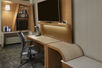 a room with a desk with a television and a chair at Courtyard by Marriott Oshawa in Oshawa