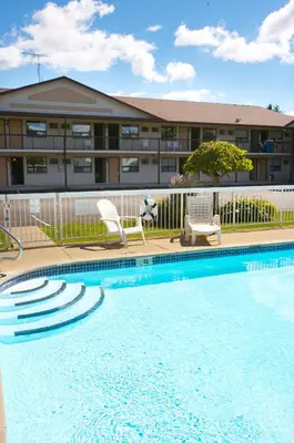 a swimming pool with two chairs and a building at Howard Johnson by Wyndham Niagara Falls in Niagara Falls