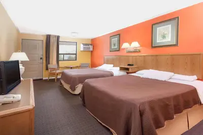 a hotel room with two beds and a flat screen tv at Howard Johnson by Wyndham Niagara Falls in Niagara Falls