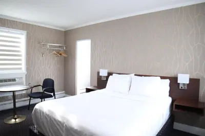a bedroom with a white bed and a desk and a table at Walkerton Inn Motel in Walkerton