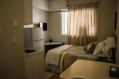 a small hotel room with a bed and a refrigerator at Saint Lawrence Residences and Suites in Toronto