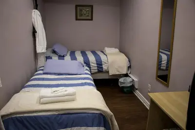a small room with two beds and a mirror at Saint Lawrence Residences and Suites in Toronto