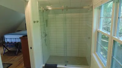 a shower with a glass door in a bathroom at Carriage House On Kent in Niagara on the Lake