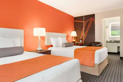 two beds in a hotel room with orange walls at Howard Johnson by Wyndham Gravenhurst in Gravenhurst