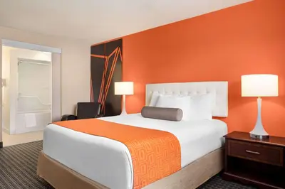 a bedroom with a large bed with an orange wall at Howard Johnson by Wyndham Gravenhurst in Gravenhurst