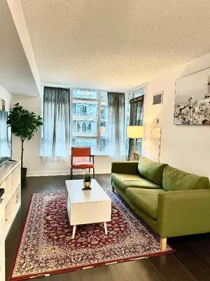 a living room with a green couch and a coffee table at Cozy Condo near CN Tower in Toronto