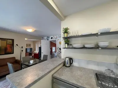 a kitchen with a counter top and a living room at Comfortable and Convenient Apartment in Central Niagara in St. Catharines