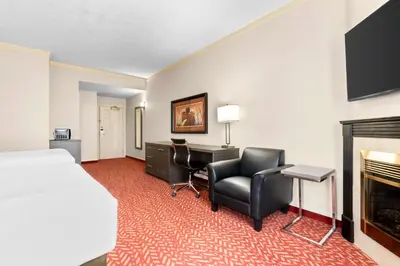 a hotel room with a bed and a desk and a fireplace at Best Western Inn On The Bay in Owen Sound