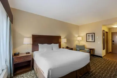 a hotel room with a large bed and a chair at Best Western Plus Walkerton Hotel & Conference Centre in Walkerton