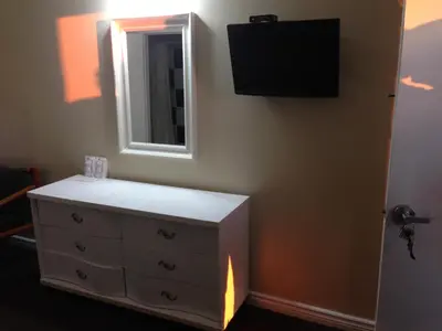 a bedroom with a dresser and a mirror at Davidson Motel in Paris