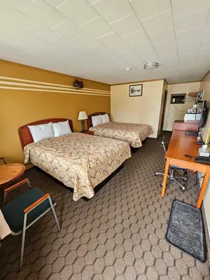 a hotel room with two beds and a desk at Forest Plaza Motel in Mount Forest