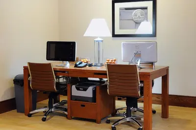 an office with a desk with a computer and two chairs at Four Points by Sheraton Cambridge Kitchener, Ontario in Cambridge