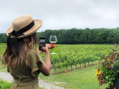 a woman taking a picture of a glass of wine at Maison Doucet in Niagara Falls